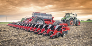 Fendt tractor pulling a HORSCH planter across a freshly tilled field under a dramatic orange sky, showcasing advanced planting equipment in action.