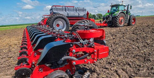 Close-up view of a HORSCH Maestro planter attached to a Fendt tractor, planting in neat rows across a tilled field under a bright blue sky.