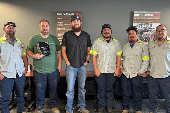Pasco service department team at Agri-Service standing together in front of company values signage