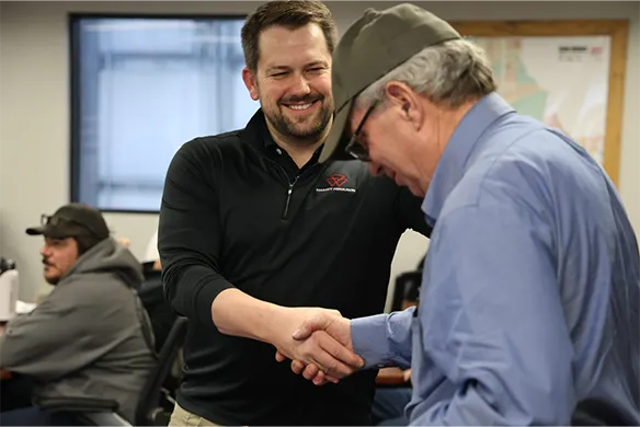 Agri-Service employee Steve Bughi shaking hands with another employee celebrating his retirement.